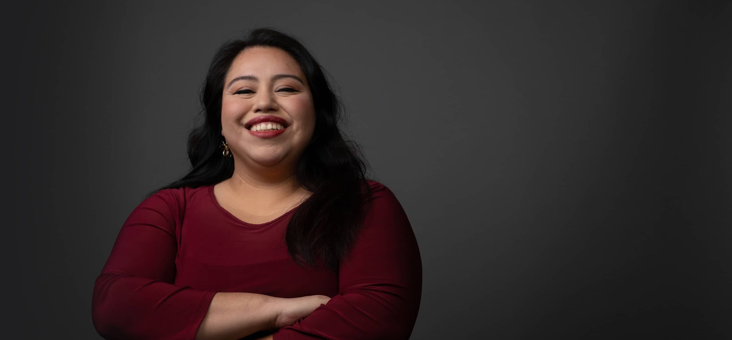 Smiling woman in a red top with arms crossed