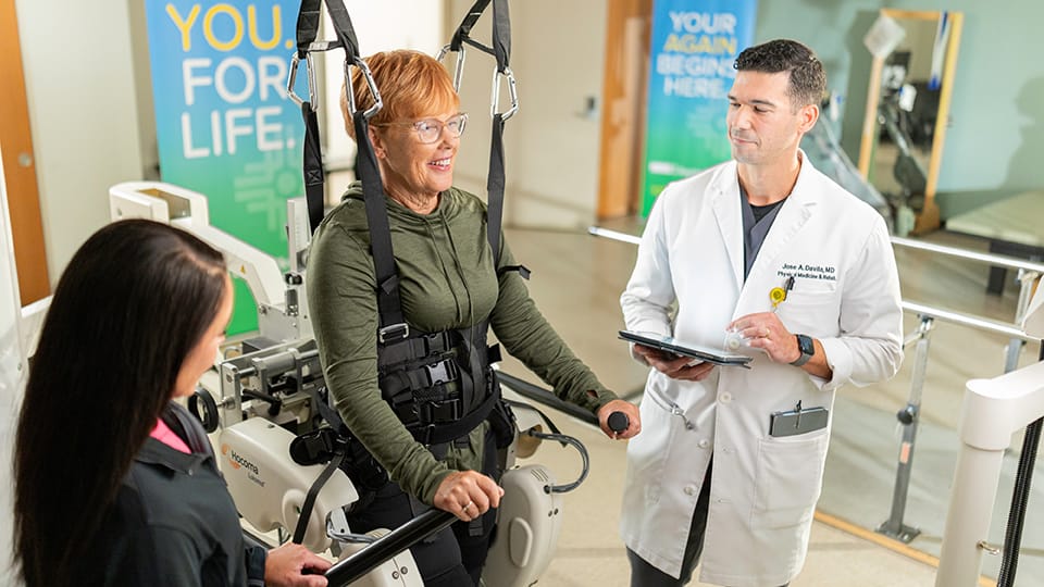 A woman who had a stroke relearns to walk using the Lokomat unweighted treadmill.