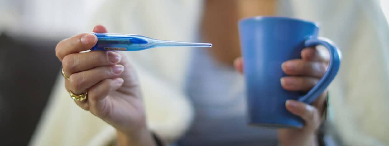 Women looks at thermometer and holds coffee