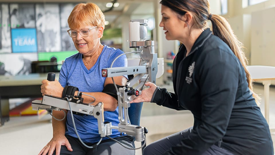 Woman who had a stroke uses Armeo Spring robotic-assisted therapy device alongside therapist to regain hand and arm function.