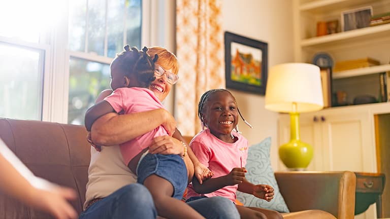 Woman spends time with her grandchildren in her living room.