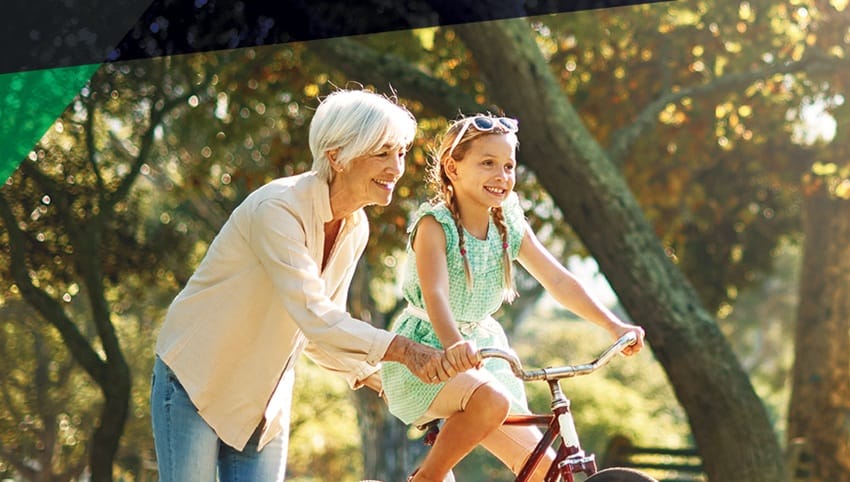 An older woman helping a child ride a bike