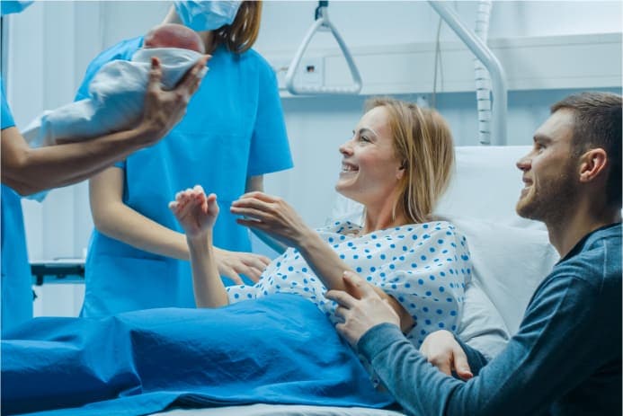 Woman and man being handed a newborn child after delivery