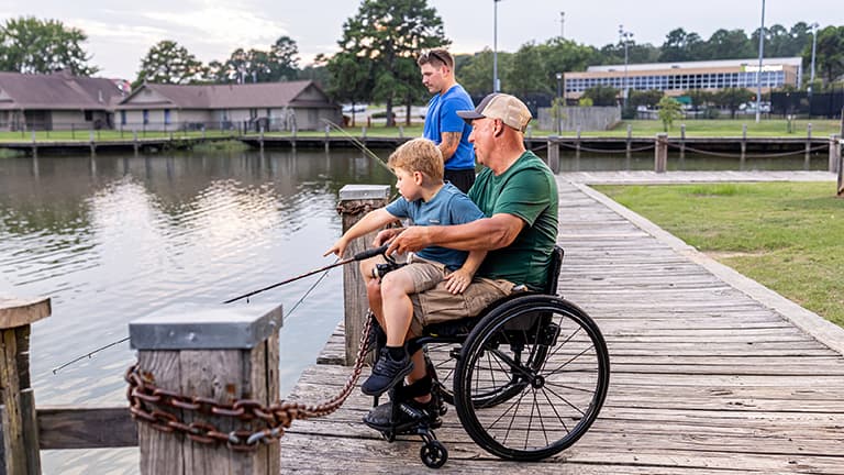Man in wheelchair goes fishing with his son and grandson.